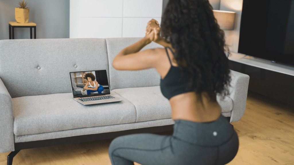 Home Workout Tips: A Woman Doing Squats At Home In front Of the Laptop 