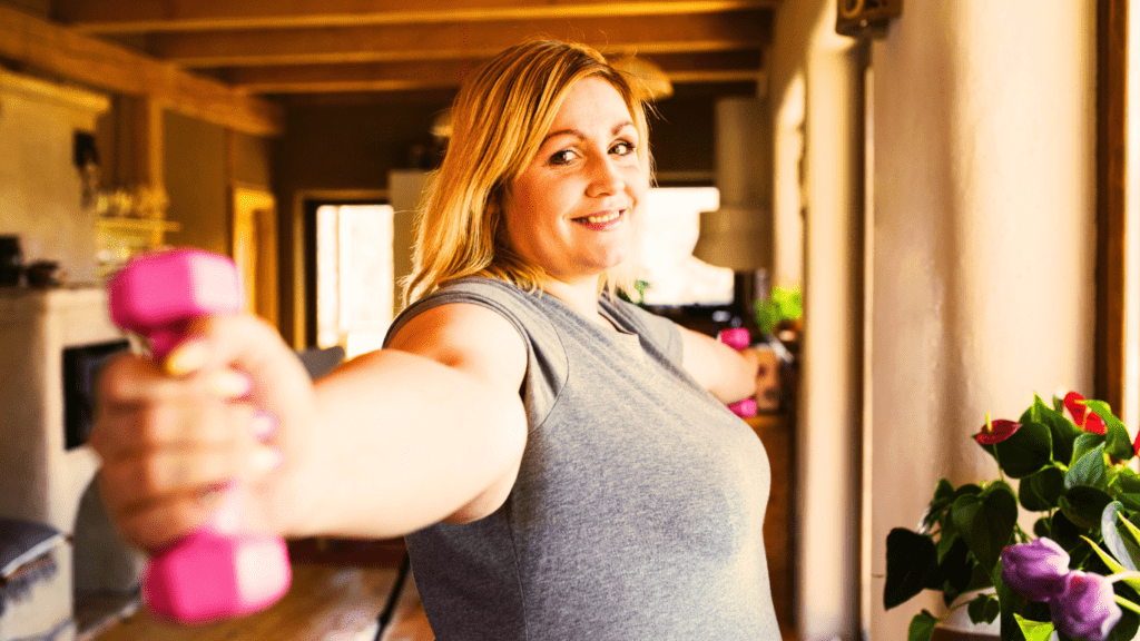 A woman at her home holding two small dumbbells and working out