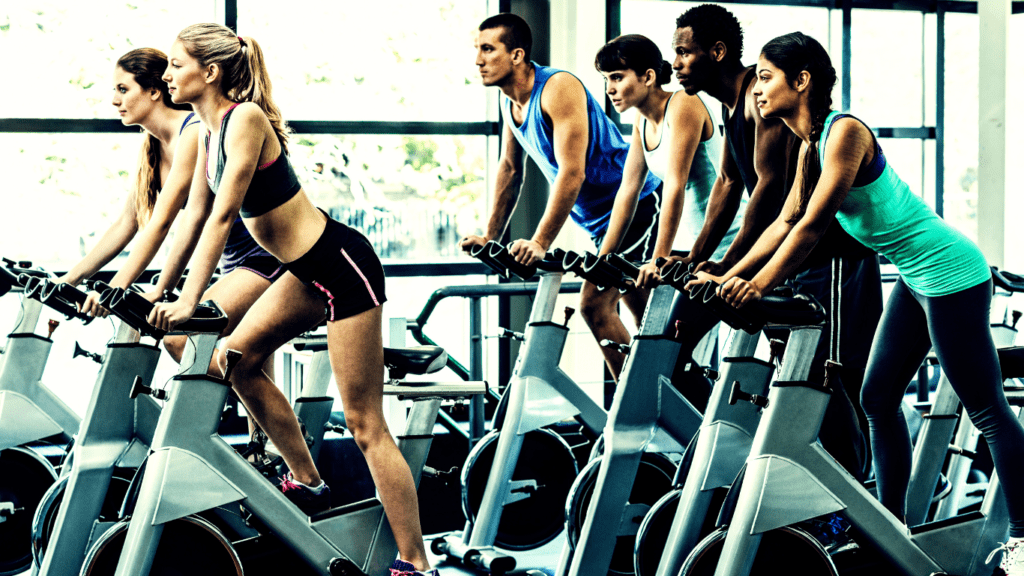 A Class Doing Standing Exercise On Their Stationary Bikes