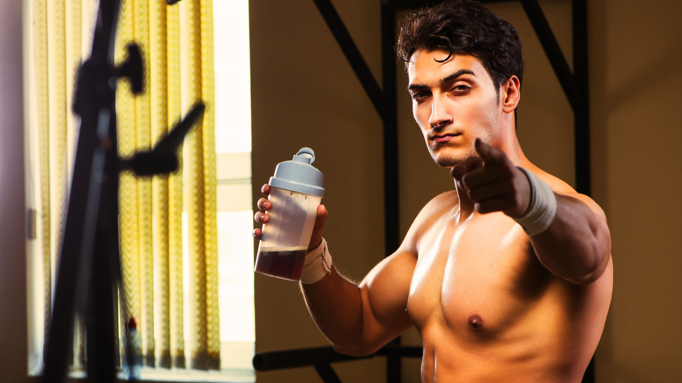 A Fit Man Holding Protein Shake And Pointing At The Camera 