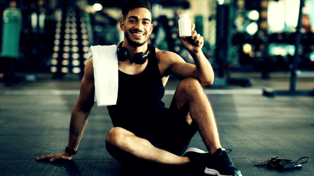 A Man Sitting In The Floor Of The Gym And Holding A Supplement 