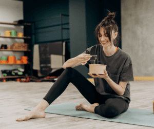 a woman eating on a yoga mat