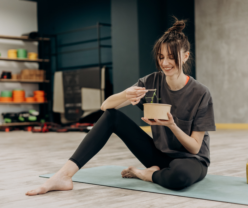 a woman eating on a yoga mat