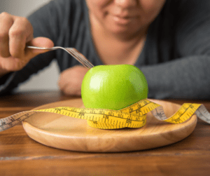 a woman on a diet watching an apple in a plate