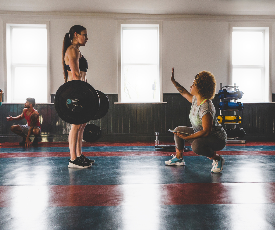 a trainer and a trainee women powerlifters at the gym