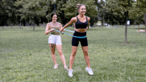 two women outdoor doing ab exercise with a resistance band