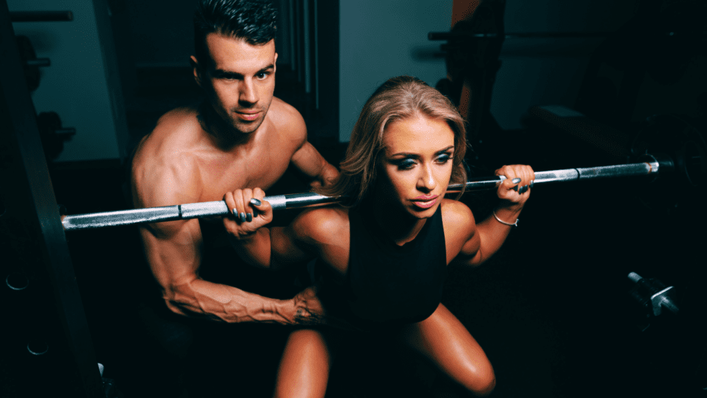 A Beginner Woman Powerlifter Doing Squats With The Help Of A Workout Male Partner 