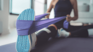 a woman working out for back muscle at home with a purple resistance band 