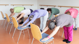 a yoga chair class with the class bending over the chair