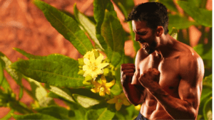 A bodybuilder next to a plant feeling happy 