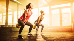 Two Women Exercising With  Kettlebells