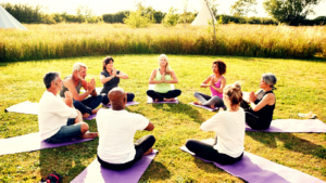 A Group of People in A Circle Practising Yoga on A Field 