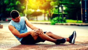 A Photo Showing An Injured Runner In Pain Sitting On The Road 