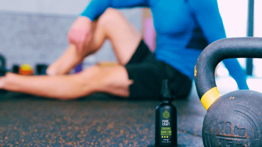 CBD Drops Next To A Kettlebell And A Man Who Is Doing Fitness Workout Using CBD For His Performance 