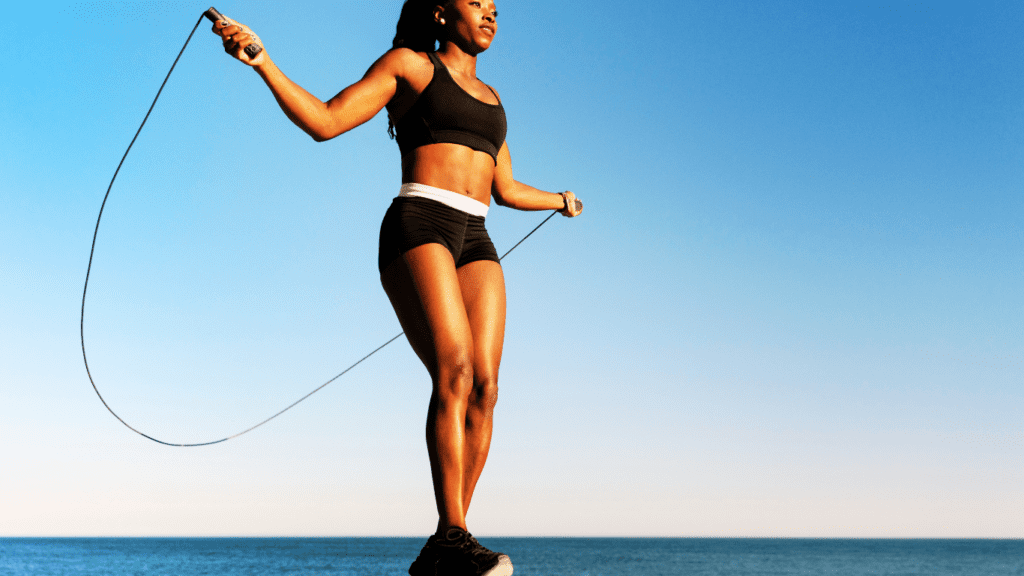 Ebony with fitness body skipping on the beach 