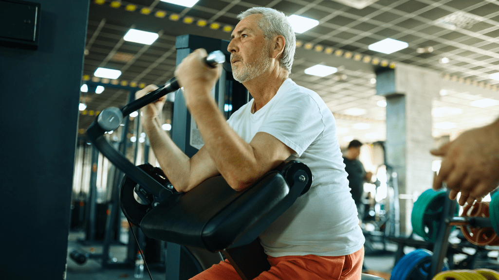 An elder man doing biceps curl scott machine